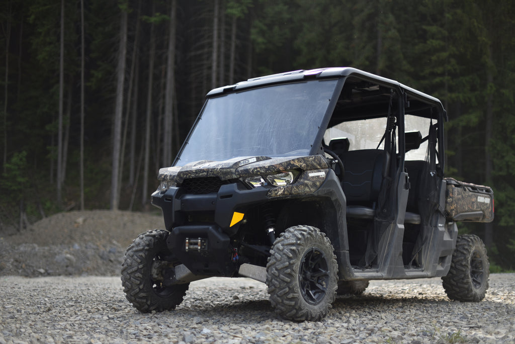 Black UTV on a gravel surface with a forest background